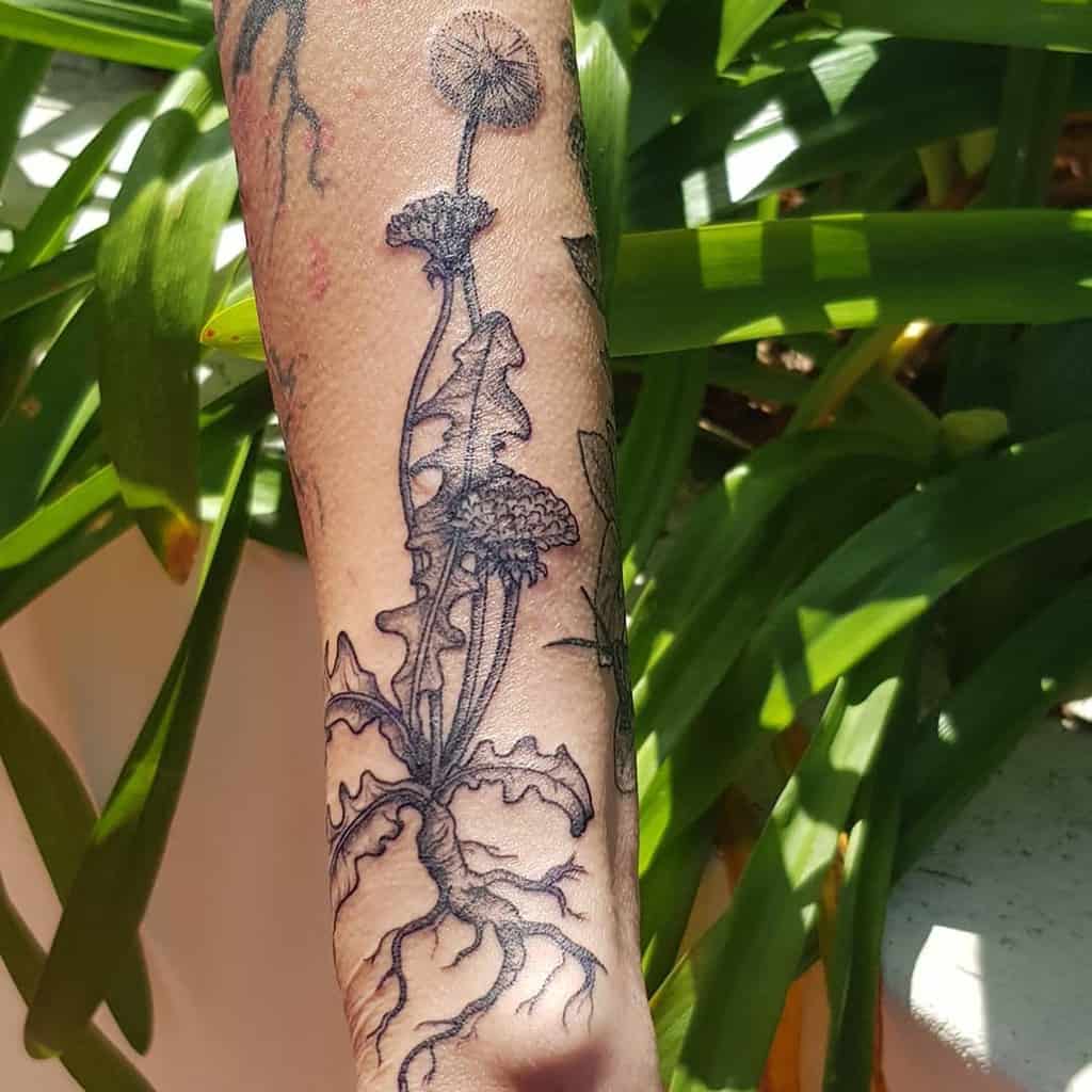 This tattoo beautifully depicts a dandelion with roots, symbolizing growth and connection, rendered in intricate black ink.