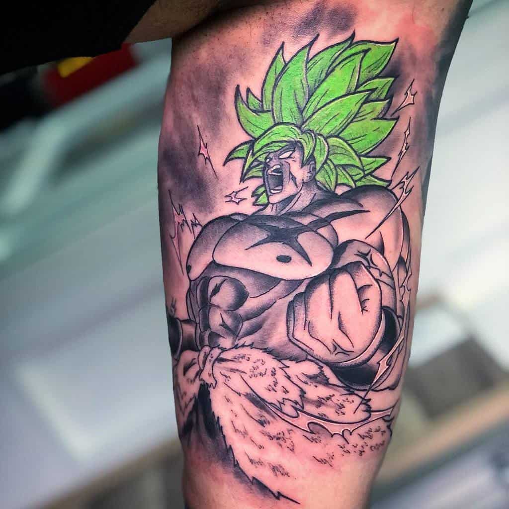 A tattoo of Broly from Dragon Ball in Super Saiyan form, with green hair and intense energy emanating from his body, in black and white with green highlights.