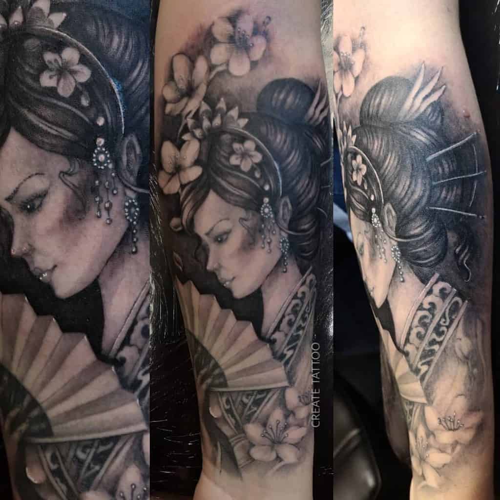 Black and gray sleeve tattoo of a Geisha with intricate floral hair ornaments, delicate shading, and a detailed fan, blending realism and elegance.