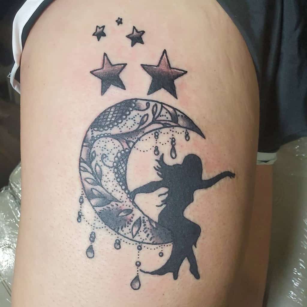 Thigh tattoo featuring a decorative lace crescent moon with beaded accents, a silhouetted woman, and shaded stars above.