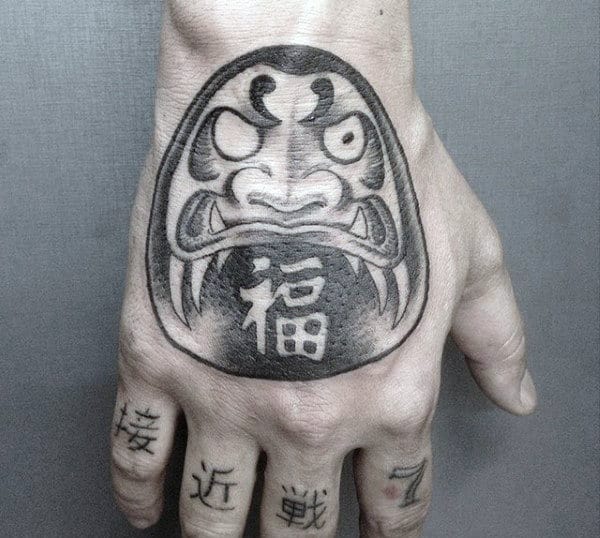 Black And Grey Shaded Daruma Doll Hand Tattoo On Man