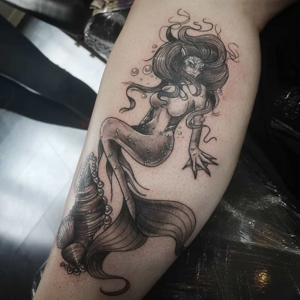 Tattoo of a stylized siren with flowing hair and intricate details on a forearm