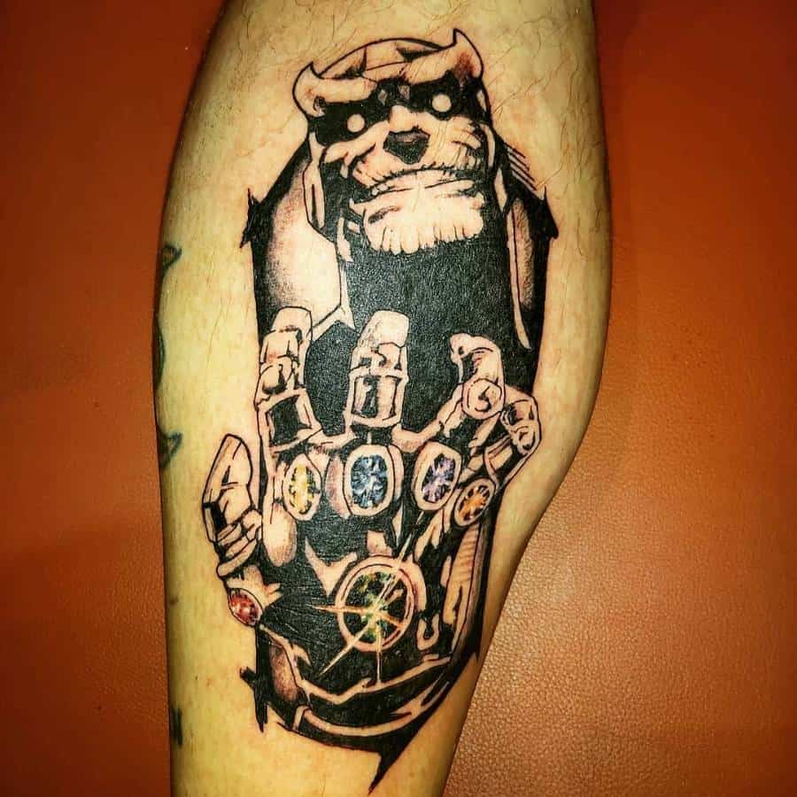 Bold black and grey tattoo of Thanos with glowing eyes, reaching forward with the Infinity Gauntlet, detailed with colorful Infinity Stones
