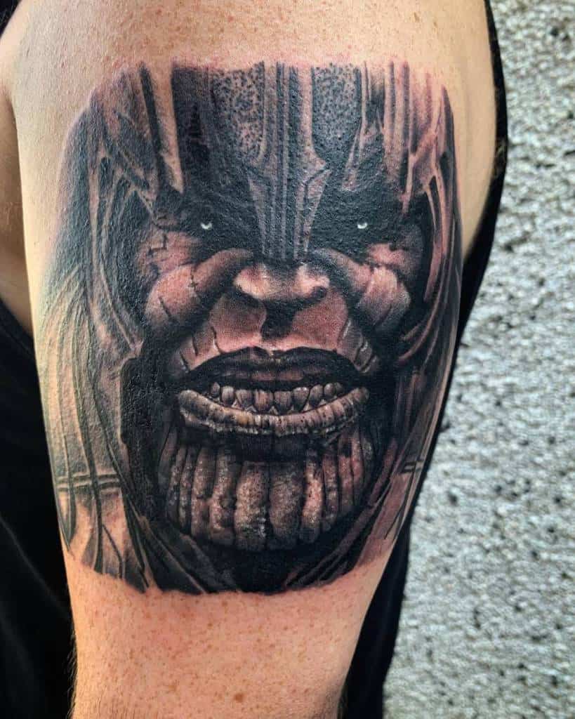 A black and gray tattoo of Thanos' face, showcasing his menacing expression with highly detailed features and shading around the chin and jawline