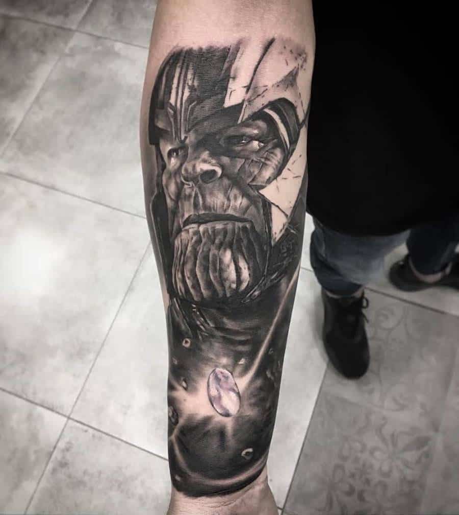 A black and gray tattoo of Thanos' face with intricate shading, featuring the gauntlet with a glowing stone