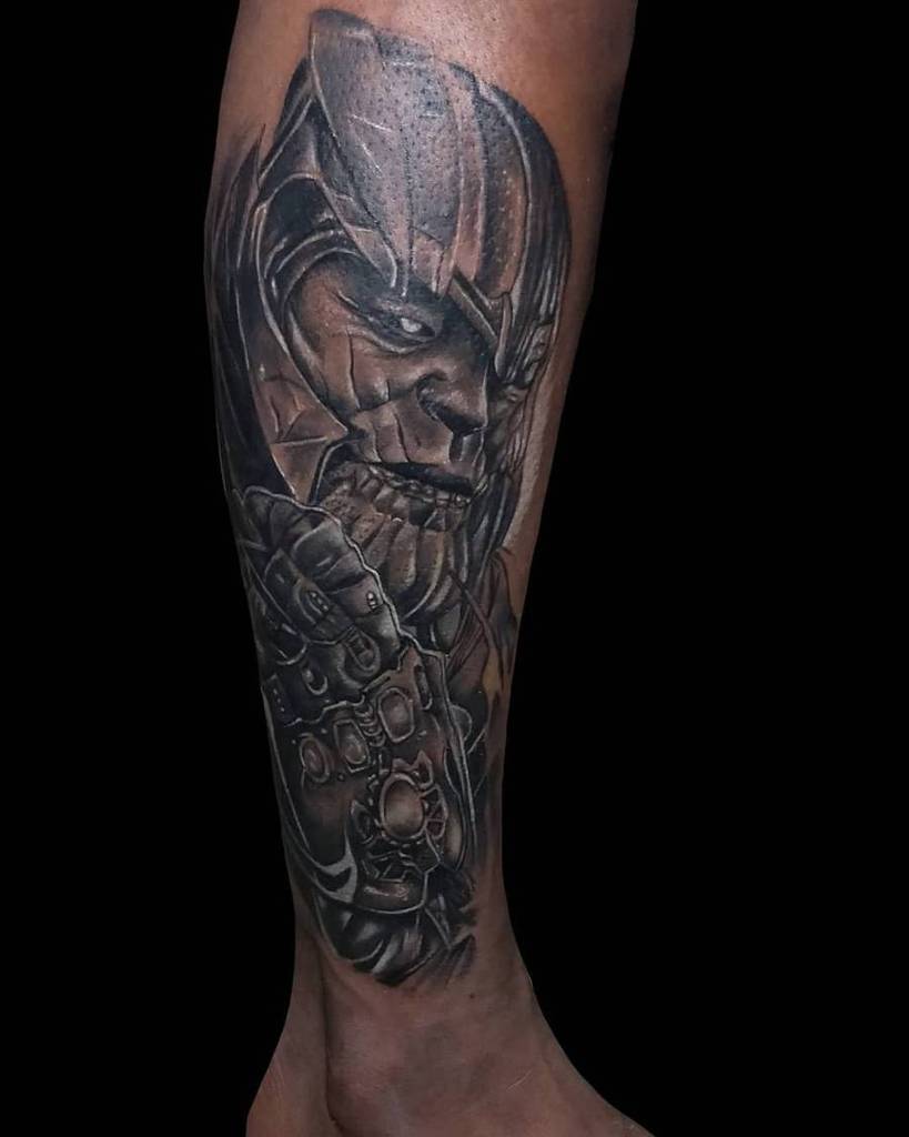 A detailed black and gray tattoo of Thanos, and the gauntlet with the Infinity Stones