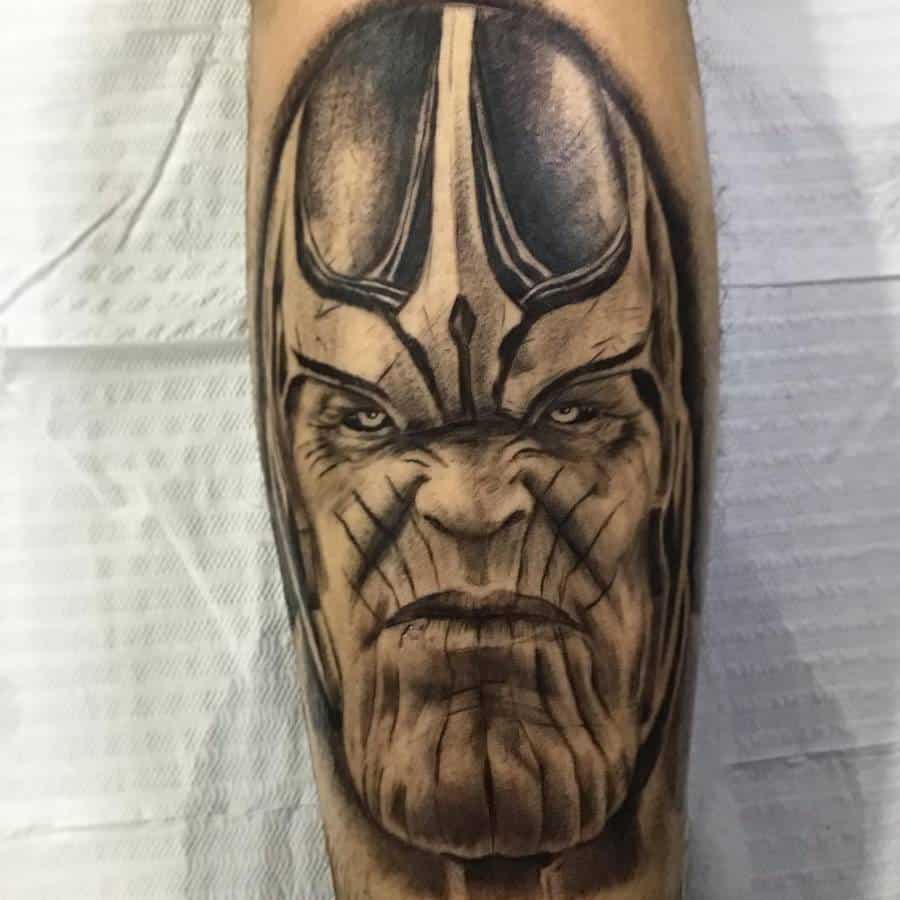 A black and gray tattoo of Thanos' face, featuring intense details, strong shading, and a fierce expression