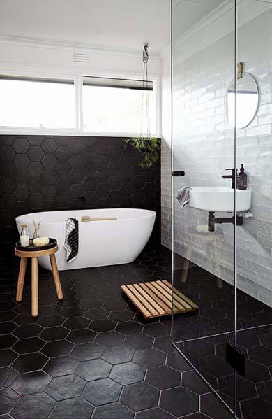 Stylish bathroom with black hexagonal floor tiles, a freestanding tub, and glass shower.