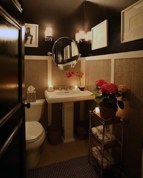 Modern bathroom with textured walls, round mirror, and warm candle lighting.