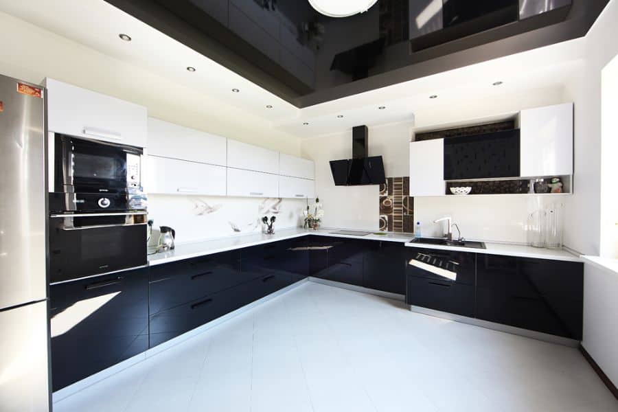 Spacious kitchen with glossy black lower cabinets, white upper cabinets, and a modern ceiling design.