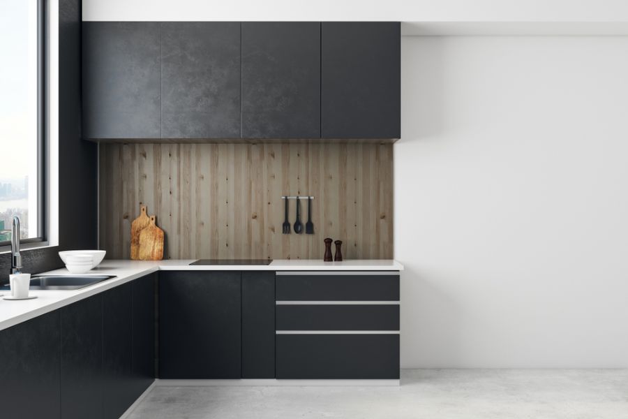 Modern kitchen with black cabinets, white countertops, and wood panel backsplash.