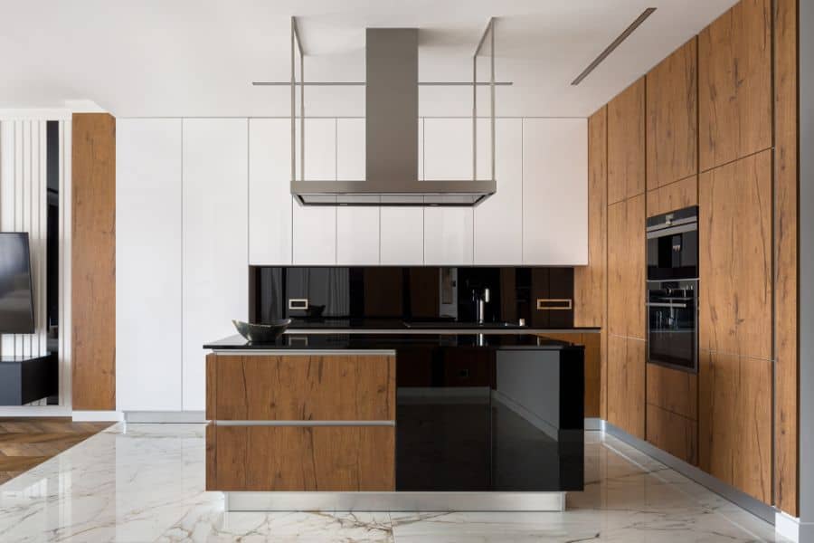Modern kitchen with wood-paneled cabinets, black island, white upper cabinets, and range hood.