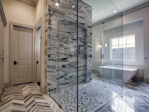 Modern bathroom with a marble shower, glass enclosure, herringbone tile floor, and freestanding bathtub