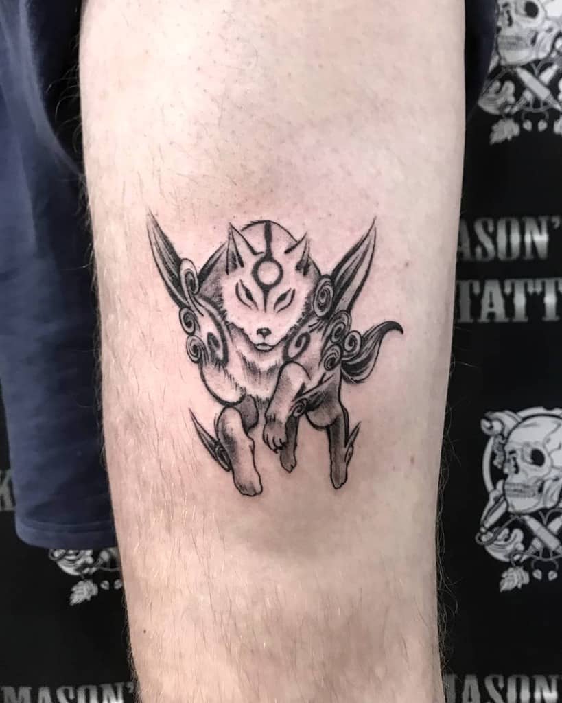 Black and white Okami tattoo of Amaterasu in a dynamic pose with intricate swirling details, capturing the spirit of the mythical wolf