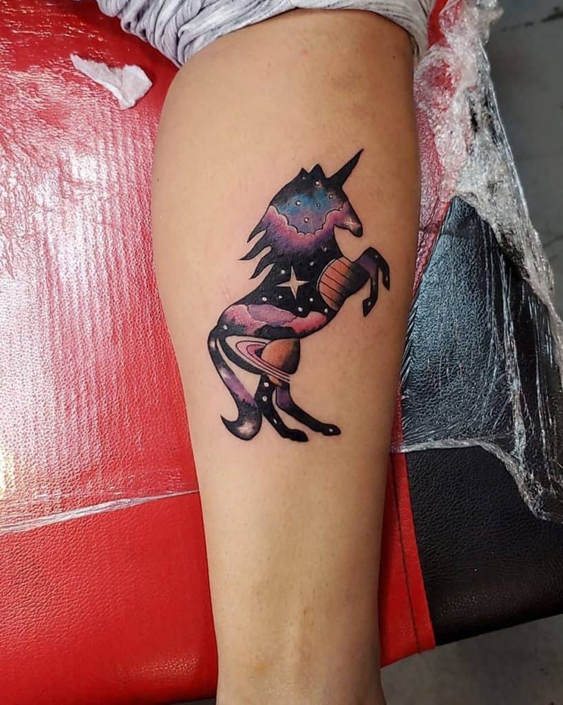 Colorful tattoo of a rearing unicorn filled with a cosmic galaxy design, featuring planets, stars, and nebula-like hues for a mystical effect.
