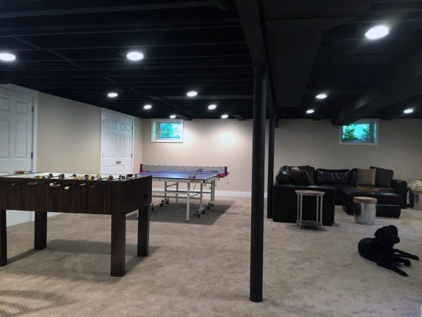 Basement with black exposed ceiling, game tables, sectional sofa, and recessed lighting.