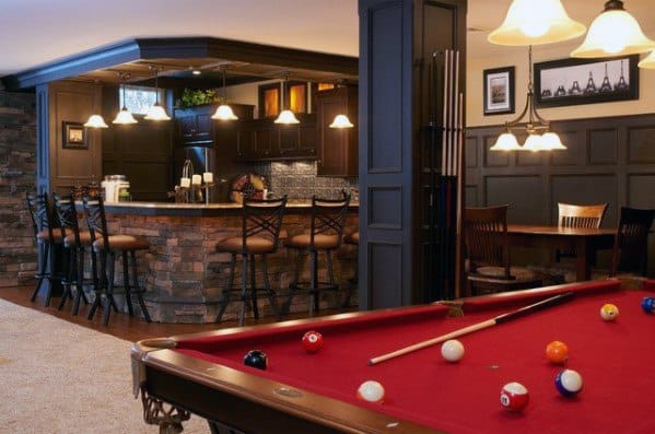 Basement with vintage wet bar, red snooker table, and dark paneled columns.