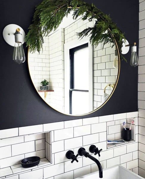 Stylish bathroom with round mirror, white subway tiles, and black wall-mounted faucets.