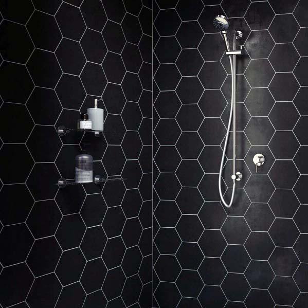 Modern shower with black hexagonal tiles, sleek fixtures, and minimalist shelving.