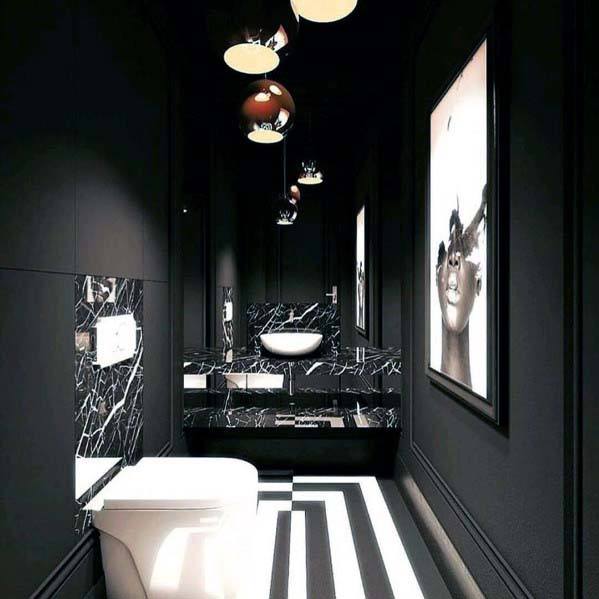 Luxurious black bathroom with marble accents, black and white striped floor, and modern artwork.