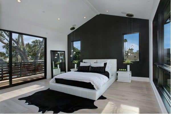 Spacious black bedroom with white accents, vaulted ceiling, and large glass doors to a balcony.
