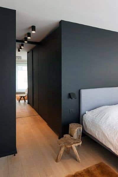 Minimalist black bedroom with wooden flooring, simple furniture, and soft lighting accents.