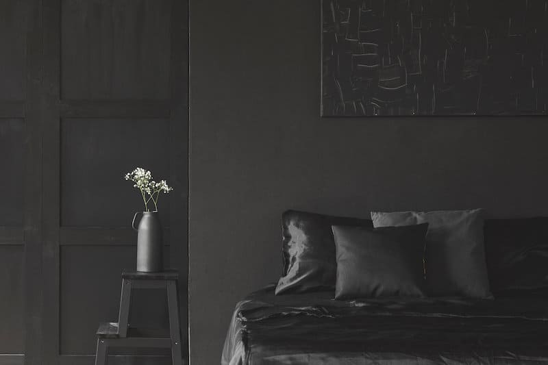 all black bedroom with vase with white flowers