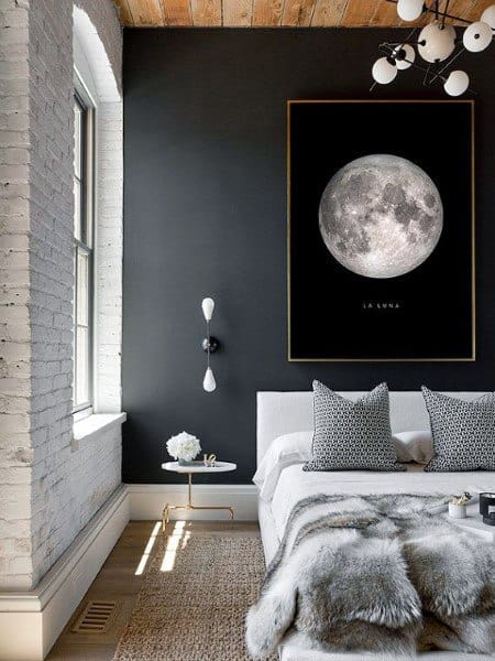 Modern bedroom with black accent wall, moon artwork, and cozy gray bedding with fur throw.