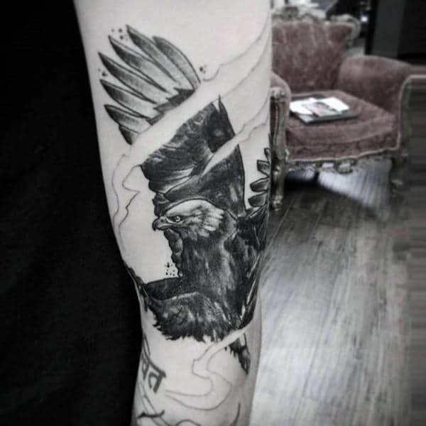 A detailed black and white tattoo of an eagle with spread wings on a person's arm