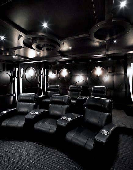 A luxurious home theater with plush black leather recliners and softly dimmed lighting
