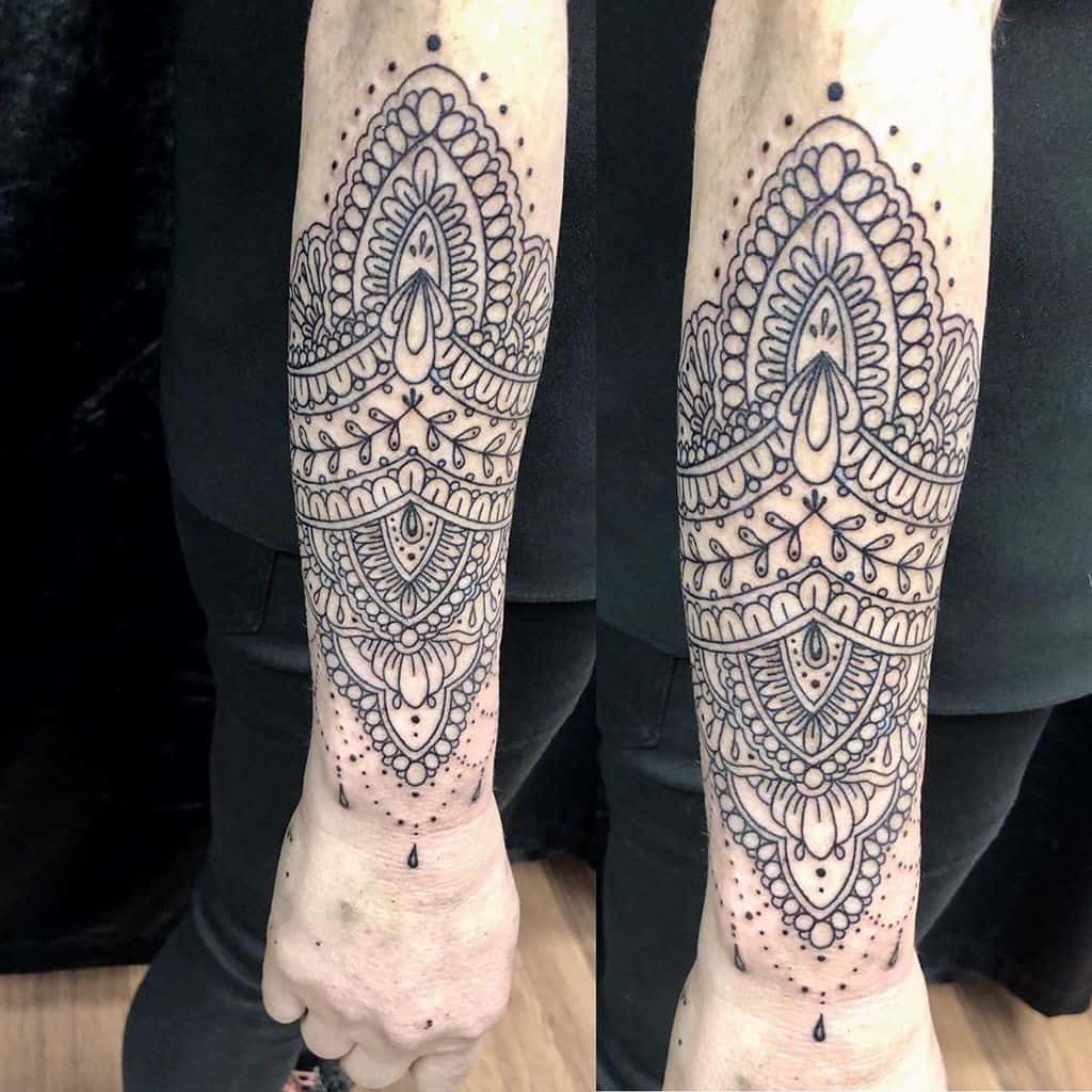 Intricate forearm tattoo featuring symmetrical lace-inspired patterns with delicate ornamental details and fine linework for an elegant look.