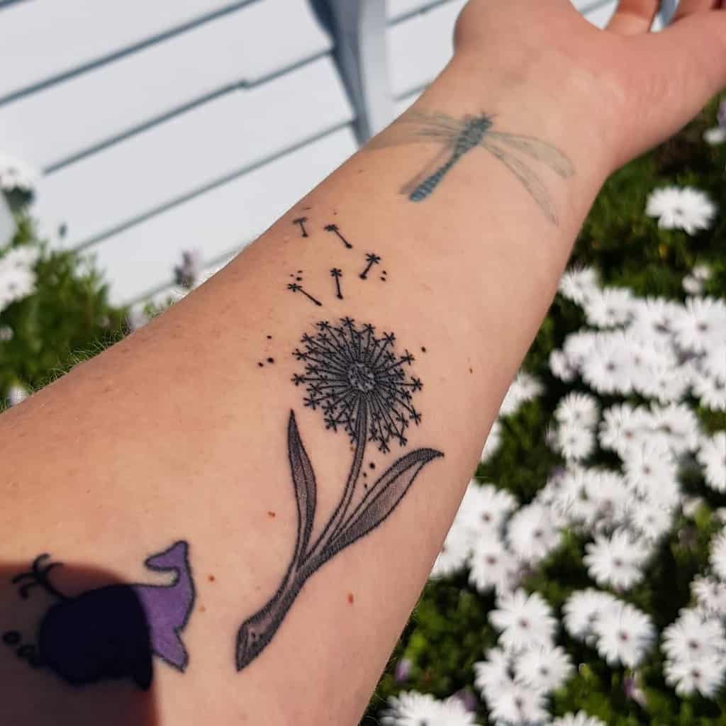 This tattoo depicts a delicate dandelion with seeds floating away, symbolizing freedom and the journey ahead.