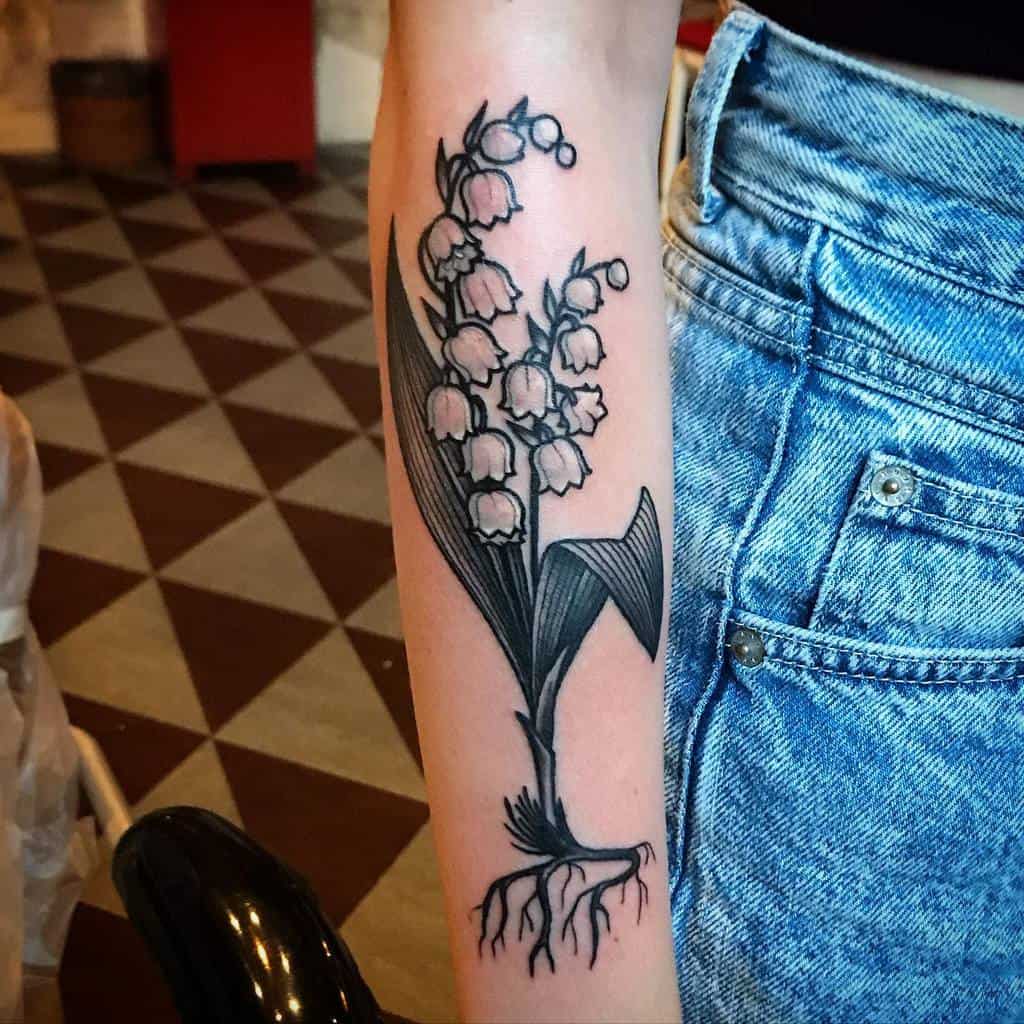 Bold black and grey Lily of the Valley tattoo, featuring detailed shading, strong line work, and visible roots for a natural touch