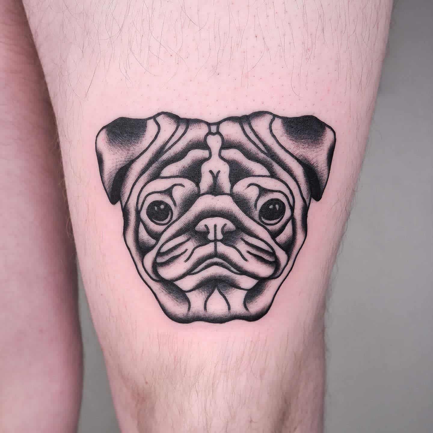 Black and grey tattoo of a pug's face with detailed shading 