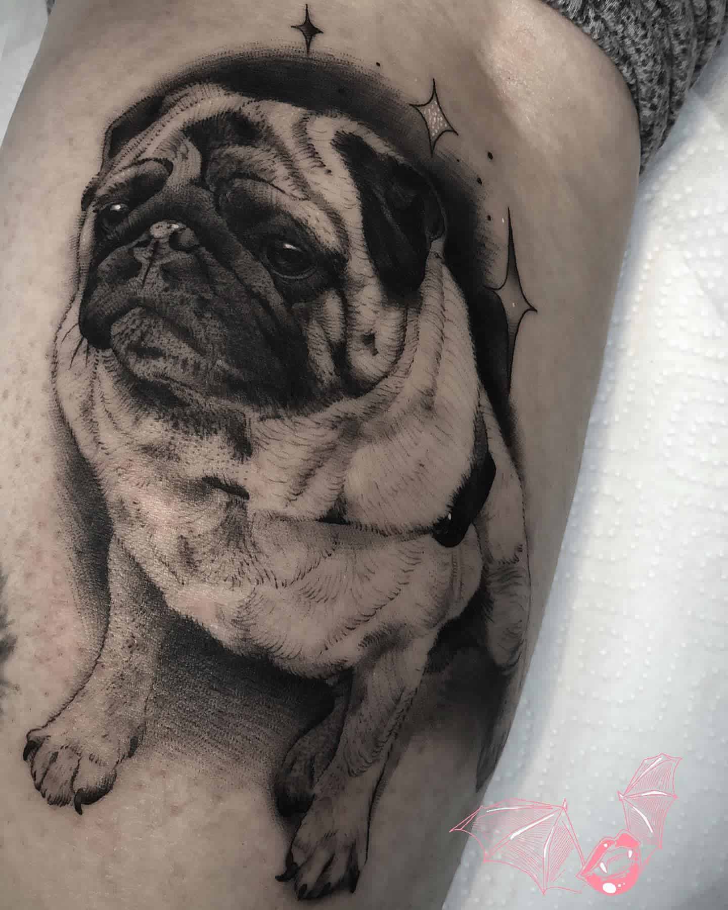 Tattoo of a pug wearing a collar, with three star-like sparkles surrounding it