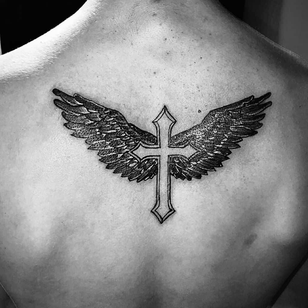 Black tattoo of a cross with detailed shading of angel wings