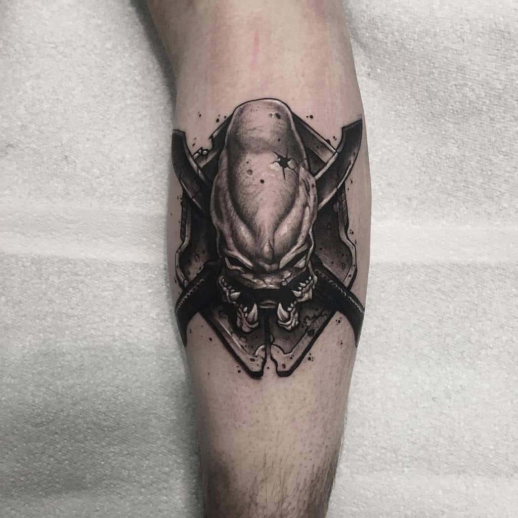 Detailed black and gray tattoo of an Elite from Halo, featuring a shield and crossed swords, inked on the calf with realistic shading.