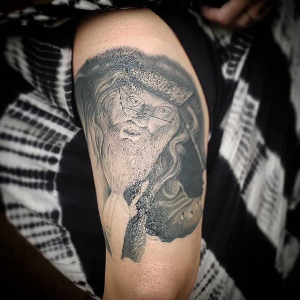 Realistic black and grey tattoo of Albus Dumbledore, capturing his wise expression, long beard, and signature half-moon glasses