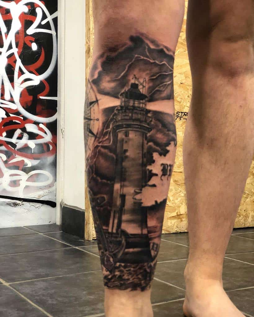 Leg sleeve tattoo of a lighthouse with storm clouds and lightning, featuring a compass and anchor