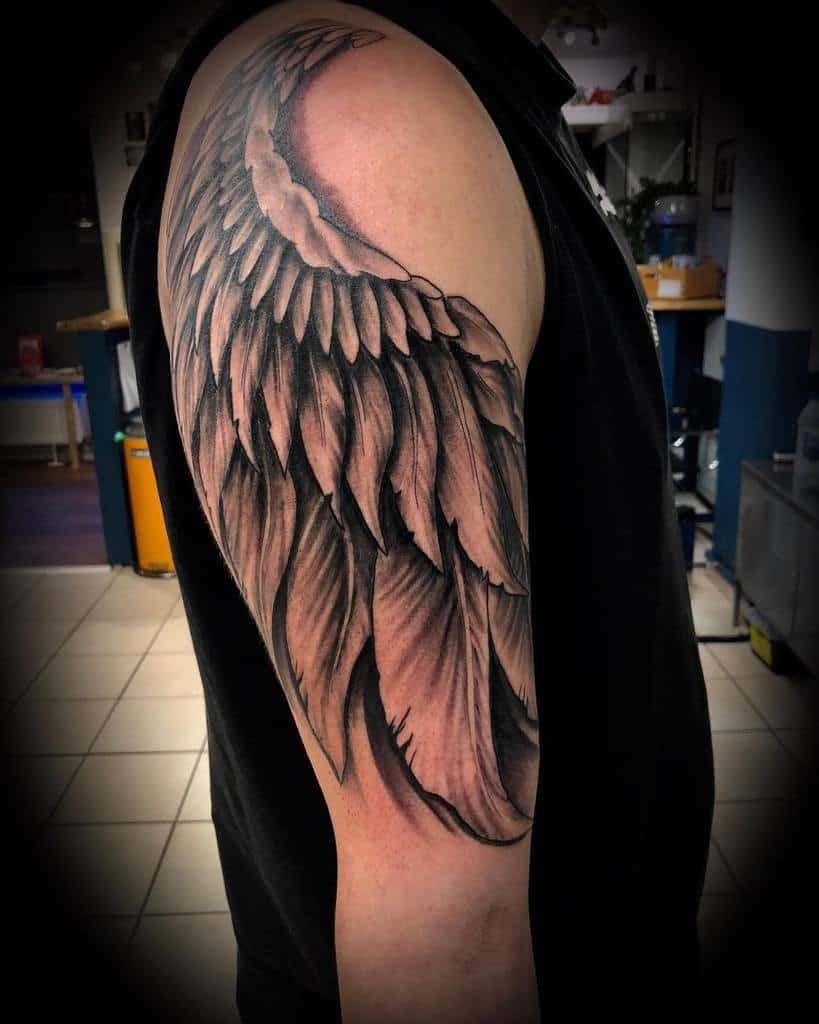 Intricate single angel wing tattoo, featuring finely detailed feathers and soft shading, giving the design a dynamic and flowing appearance