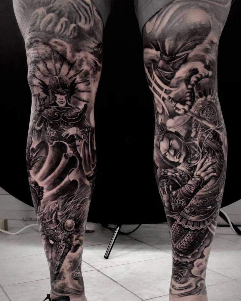Black and grey tattoo leg sleeve, featuring dramatic scenes with warriors in armor, horse with mask, trident, and swirling smoke
