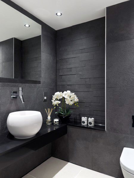 Modern half-bath with black textured walls, a sleek sink, and minimalist decor.