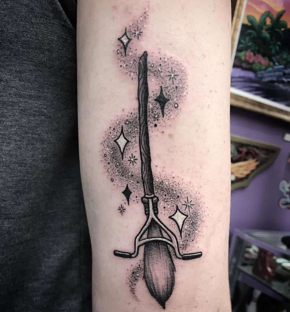Harry Potter-inspired tattoo of a broomstick with sparkling magical effects, done in black and gray dotwork style