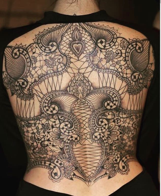 Ornate full-back tattoo featuring intricate lace patterns, floral details, and symmetrical ornamental designs for an elegant, corset-like look.