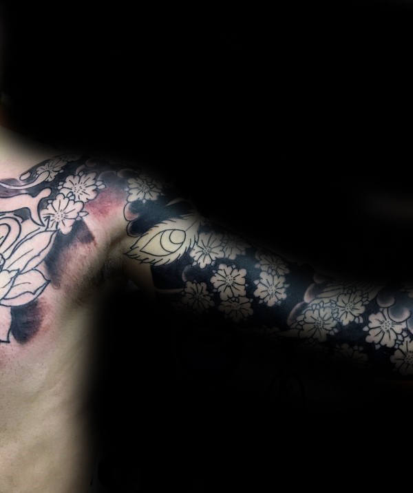 Full sleeve tattoo with bold black ink featuring intricate cherry blossom outlines, a floral chest piece, and a striking eye detail