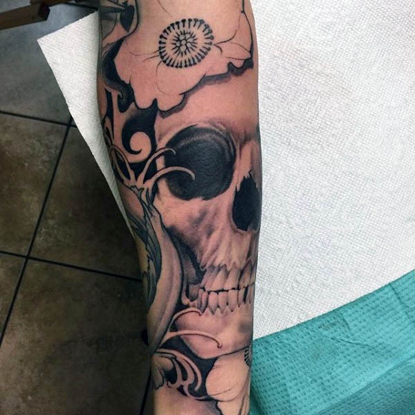Black Ink Male Tattoo Of Skull With Poppy On Forearms