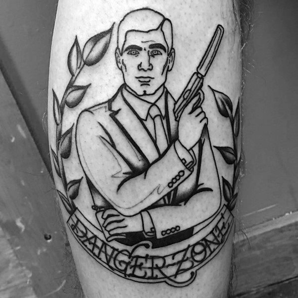 Black and grey Archer tattoo featuring a suave spy in a suit holding a gun, framed by laurel leaves and a 'Danger Zone' banner.