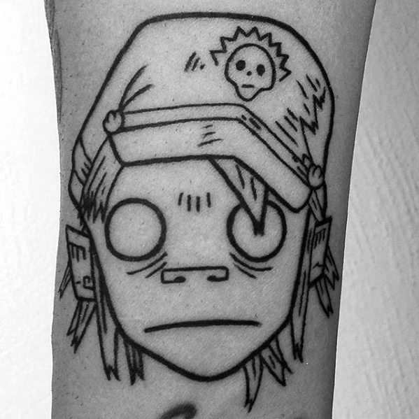 Minimalist black line tattoo of 2D from Gorillaz, showing his blank eyes, beanie with skull symbol, and signature straight-faced look.