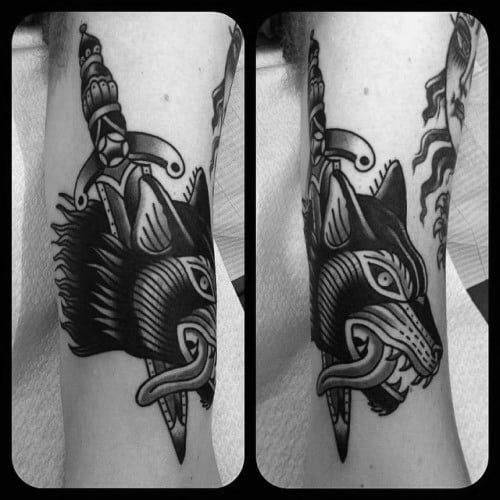 Black Ink Wolf Head With Dagger Male Traditional Arm Tattoo Ideas