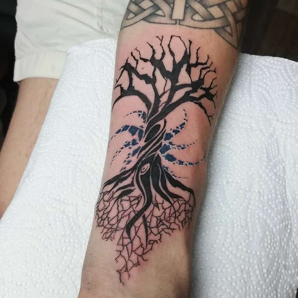 The tattoo features Yggdrasil with cracked roots and swirling cosmic elements, blending Norse mythology with an abstract, mystical style.